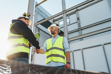 Handshake of two engineers wearing safety helmet and protect sunglasses on outdoors construction site. Meeting and hand shake of engineers and worker