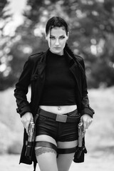 Lara Croft Tomb Raider action movie cosplay costume photoshoot with guns and weapons brunette female model Black and white version	 - obrazy, fototapety, plakaty