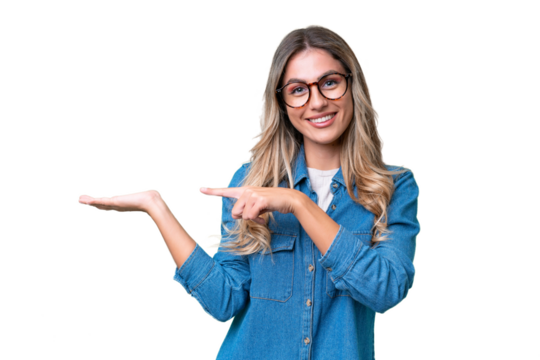 Young Uruguayan woman over isolated background holding copyspace imaginary on the palm to insert an ad