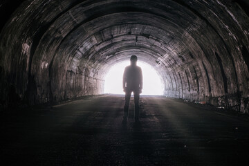 Human silhouette in the tunnel, light at the end of tunnel
