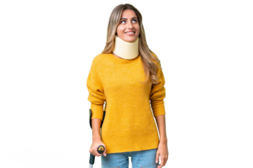 Young Uruguayan woman wearing neck brace and crutches over isolated background looking up while smiling