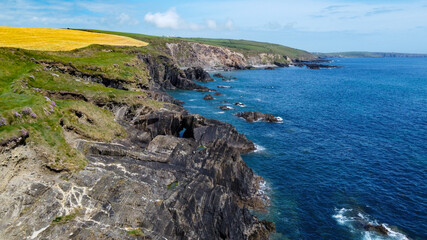 Fototapeta na wymiar Farm fields on the rocky shore of the Celtic Sea, south of Ireland, County Cork. Beautiful coastal area. Turquoise waters of the Atlantic. Picturesque stone hills. Drone point of view.