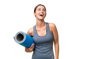 Pretty Young Uruguayan sport woman going to yoga classes while holding a mat over isolated background laughing