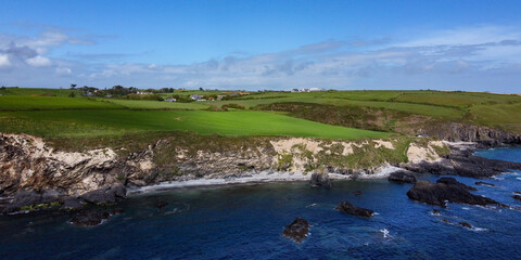Green hills on the Atlantic Ocean on a sunny spring day. Blue sky over the sea coast. The coastline of Ireland, West Cork. Aerial photo.
