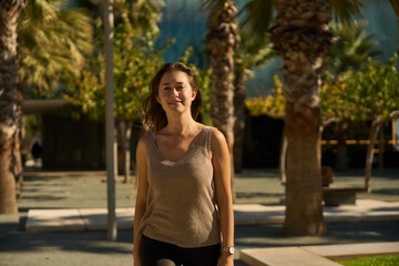 young female student walking in a park with palm trees