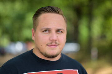 Young man with mustache standing looking up outdoors