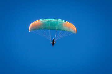 Vizille, Isere, Rhone-Alpes, France, 20 11 2022 green and orange paraglider flying in the sky