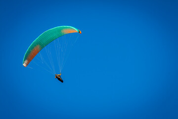 Vizille, Isere, Rhone-Alpes, France, 20 11 2022 green and orange paraglider flying in the sky