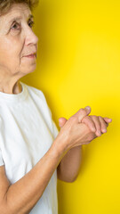 A woman in adulthood stands in a white T-shirt and looks up. Close-up of an older woman looking away from the camera.