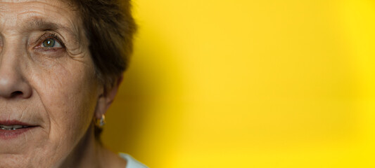 Close-up of the face of a beautiful elderly woman looking at the camera. A gorgeous older woman with natural beauty and a cheerful outlook. banner