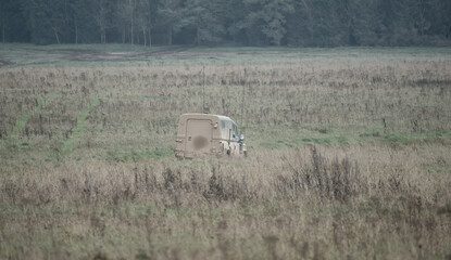 British army Land Rover Defender Wolf light utility vehicle crossing tall autumn grass meadows on a...