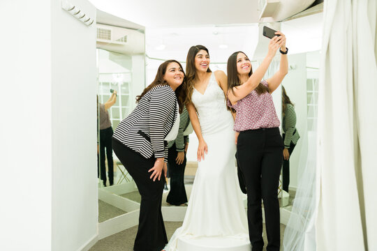 Young woman wearing a wedding dress in the dressing room with friends