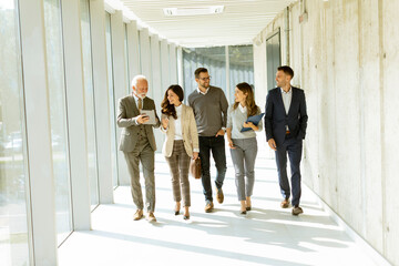 Group of corporate business professionals walking through office corridor