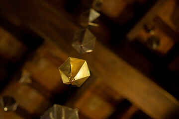 Low angle detail of a golden diamond hanging from the wooden ceiling of the granollers porch followed by two more above it