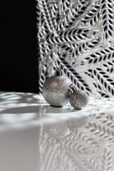 Artistic abstract chrismtas card with two shiny silver baubles, back lit decorative background and reflective surface