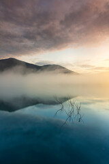 The water reflection of the sunrise breathtaking beauty nature scenery landscape with mountain mist in Khuean Phluang Reservoir nearby Khao Khitchakut National Park, Chanthaburi, Thailand
