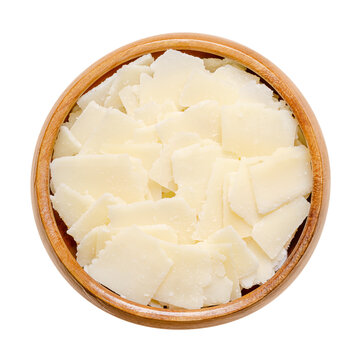 Grana Padano cheese flakes, in a wooden bowl. Italian hard cheese, similar to Parmesan, crumbly-textured, with strong savory flavor and slightly gritty texture, made from unpasteurized cow milk. Photo
