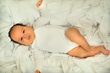 newborn baby smiles and laughs. shows emotions. baby lies on a white cloth