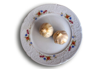 Dos cabezas de ajo en un plato blanco. 