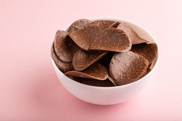 Chocolate chips on pink pastel background. side view, close up.
