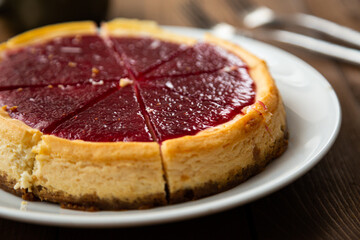 Cheesecake with raspberry jam on a wooden table
