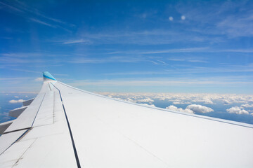 View from an airplane window showing the wing and sky with clouds