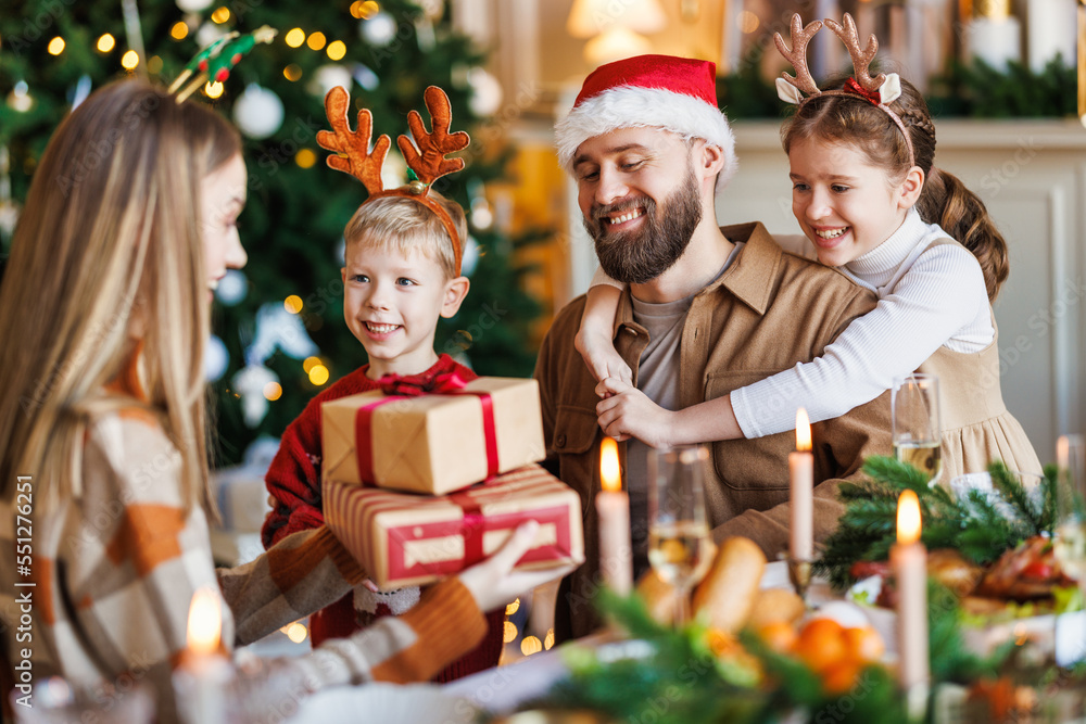 Wall mural happy family with two children celebrate christmas at home, parents and kids exchanging xmas gifts