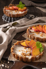 Nectarine vegan tarts with grated coconut and crunchy peanuts. Date, walnut, almond and hazelnut base.