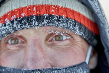 Close-up of a frozen mature man in a mask in Scandinavian clothes