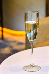 Flute glass of white wine on a table in a bar. No people.