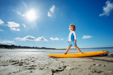 Side portrait of a blond girl stand on the surfboard at beach