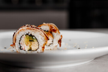 Two portions of sushi with shrimp and eel on a white plate.