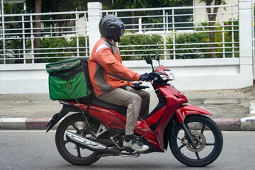 A delivery worker rides a motorcycle with a delivery box, Bangkok, Thailand