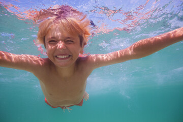 Obraz na płótnie Canvas Close-up portrait of a boy swim underwater in ocean open eyes