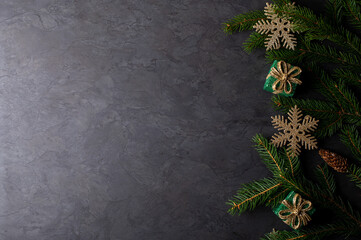 Dark christmas background with green fir branch, gift boxes and golden snowflakes, place for text