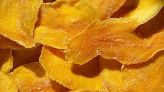 Dried mango slices close-up on a white. Top view. Closeup. Mango chips background. Dehydrated crispy fruit slices, pieces. Heap of sun-dried yellow fruit. Healthy meal. Top view, flat lay. 4K Footage