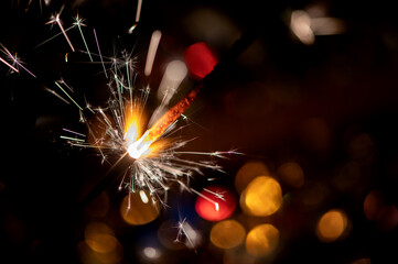 Bright glittering burning sparkler on blurred bokeh background