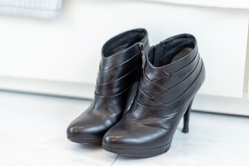 pair of black boots with high heels in front of a white closet