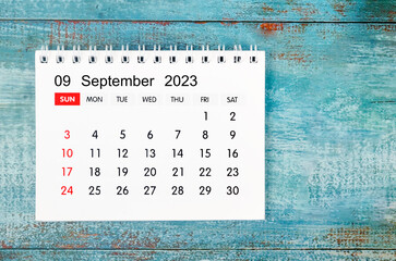 The September 2023 Monthly desk calendar for 2023 year on old blue wooden background.