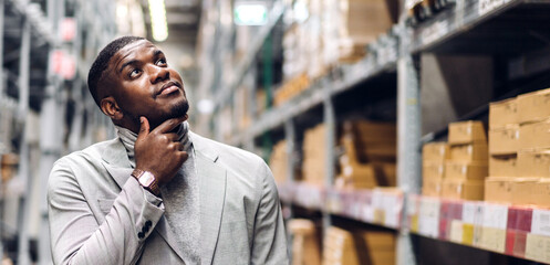 Portrait of smiling african american business man order details checking goods and supplies on shelves with goods background in warehouse.logistic and business export