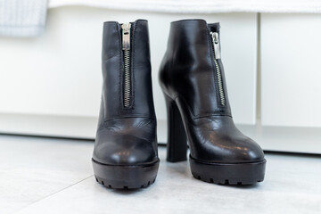 pair of black boots with high heels in front of a white closet