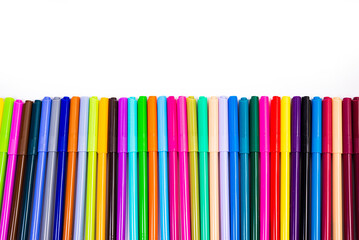 A set of multi-colored felt-tip pens in a row, rainbow on a light white banner background. Drawing markers, pencils, ink, artist tools, creativity, leisure, hobby. Colorful school supplies.