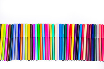 A set of multi-colored felt-tip pens in a row, rainbow on a light white banner background. Drawing markers, pencils, ink, artist tools, creativity, leisure, hobby. Colorful school supplies.