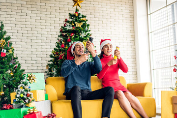 Obraz na płótnie Canvas Romantic sweet couple in santa hats having fun decorating christmas tree and smiling while celebrating new year eve and enjoying spending time together in christmas time at home