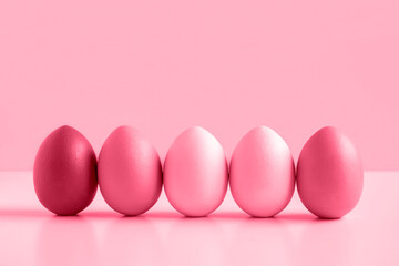 Easter banner with colorful Easter Egg in a row on white table and viva magenta background. Above view with copy space. Easter decorated eggs frame. Happy Easter card. Side view, flatlay.