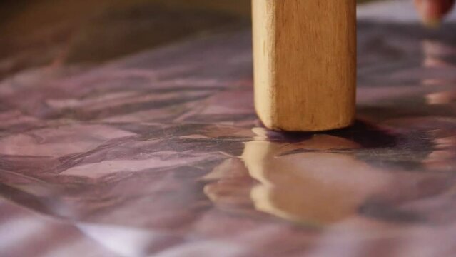 close-up video, hitting the fabric with a wooden mallet during the ecoprint printing process. make a leaf pattern on the fabric. by hitting it with a hammer made of wood.