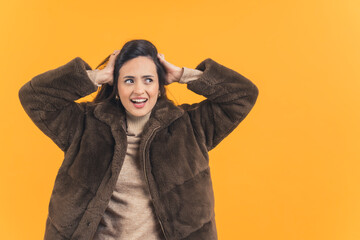 stylish Latin-American fashion model posing for a camera in winter clothes, isolated on orange background medium shot. High quality photo