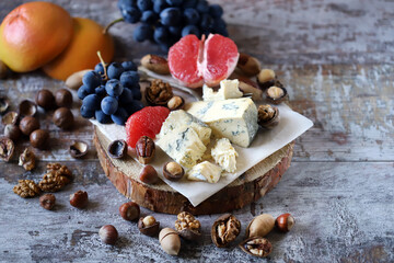 Cheeseboard. Cheese with nuts, grapefruit and grapes on a wooden board. Healthy snacks.