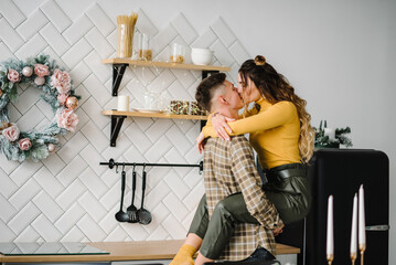 Wife hugs and kisses beloved husband, preparing for New Year and Christmas celebration, family having fun dancing in kitchen. Romantic couple in love, woman and man enjoying winter vacations in home.