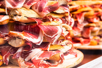 traditional Spanish bocadillos with Iberico jamon laid out in a slide on a shop window